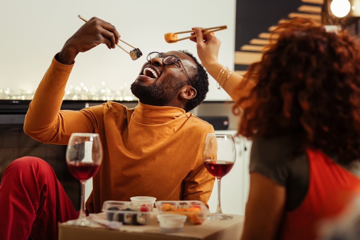 Couple having fun while eating sushi at home after fast delivery